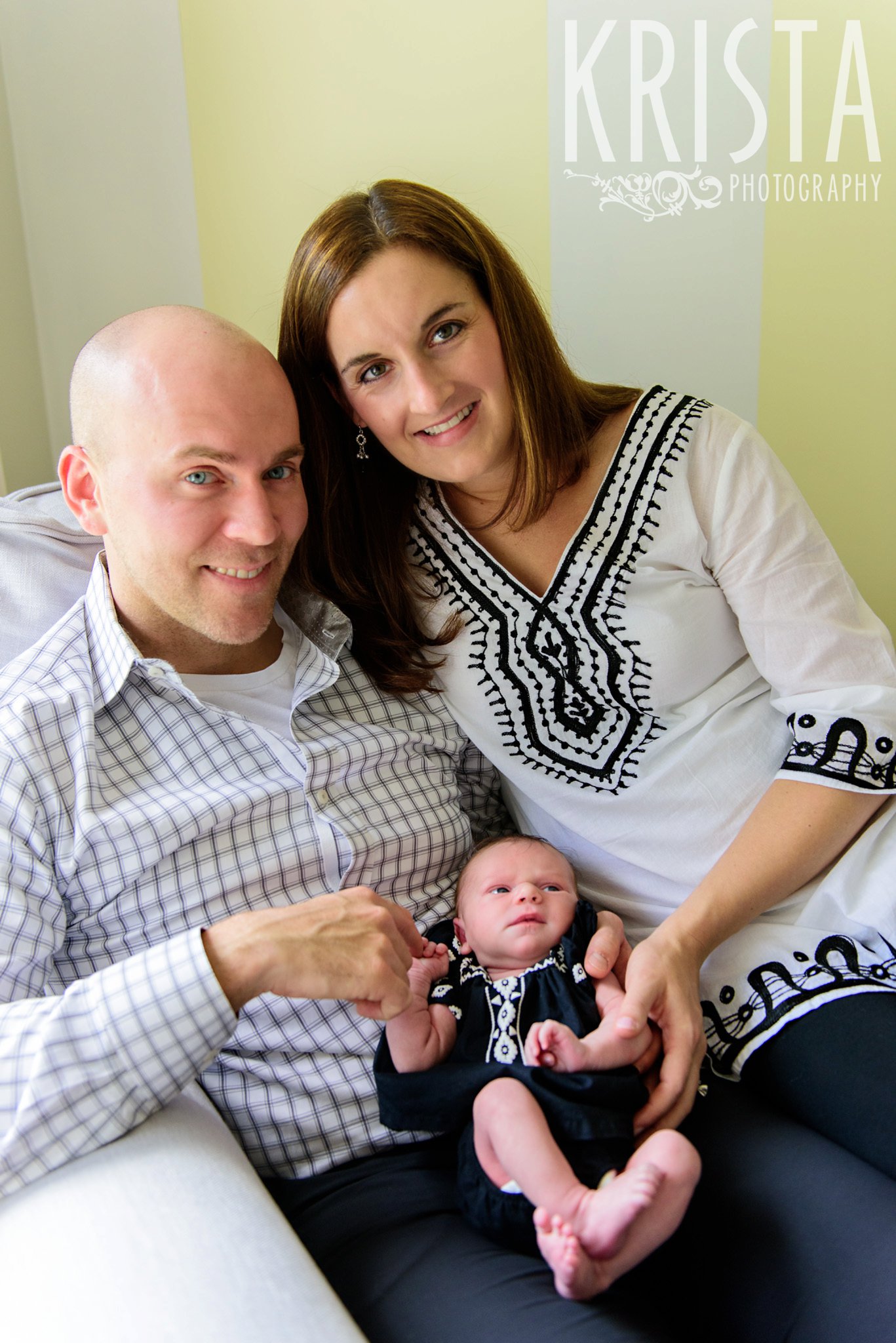 family portrait with newborn baby girl in yellow, white and gray nursery during lifestyle portrait session at family home