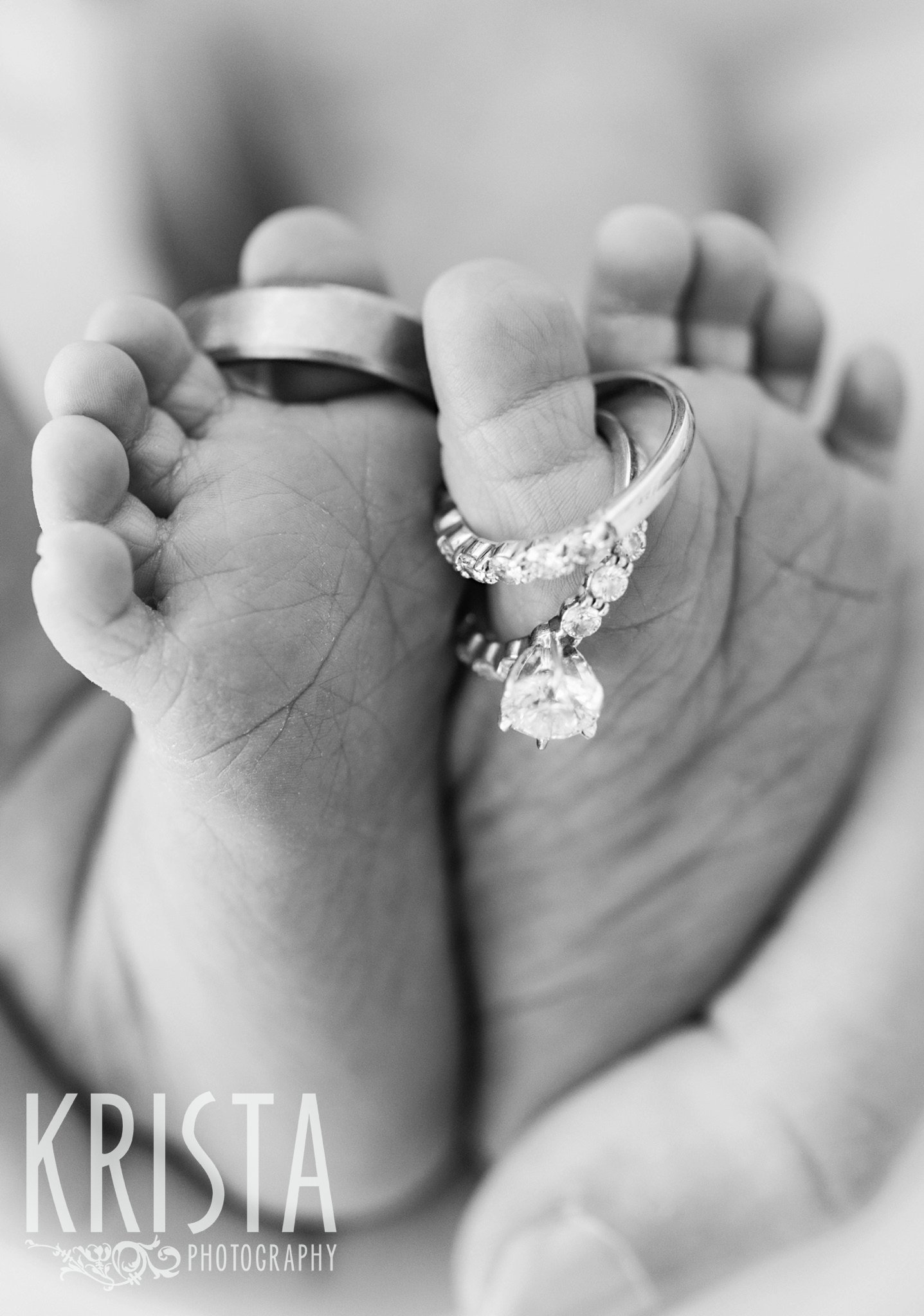 black and white image of newborn baby girl's toes with parents wedding rings