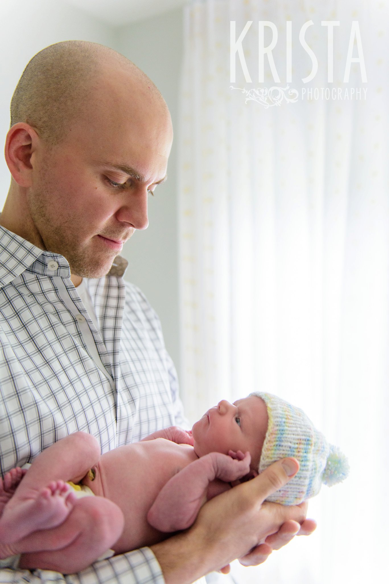 newborn baby girl with mother and father in yellow white and gray nursery during lifestyle family portrait session