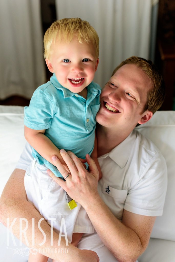father and toddler son laughing in blue and white during lifestyle family portrait session at home