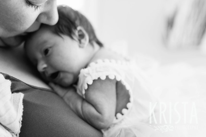 black and white mother holding newborn baby girl on chest during lifestyle family portrait session at home