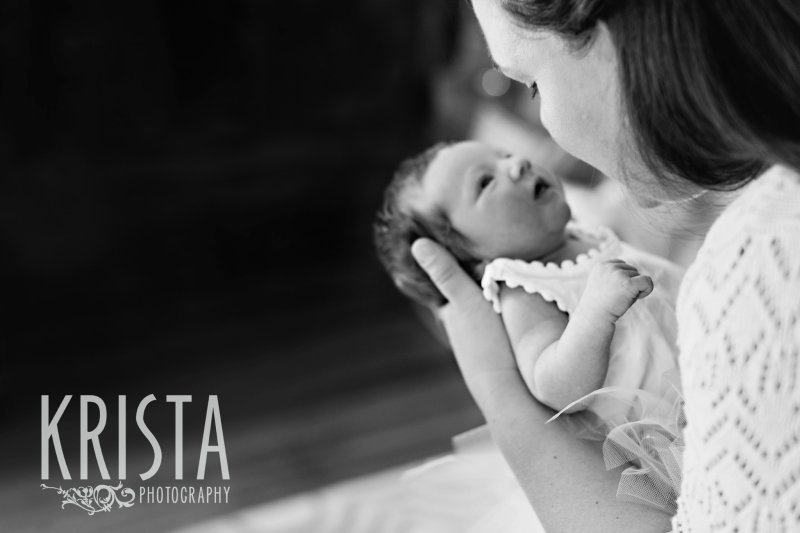 black and white mother gazing into newborn baby girl's eyes during lifestyle family portrait session at home