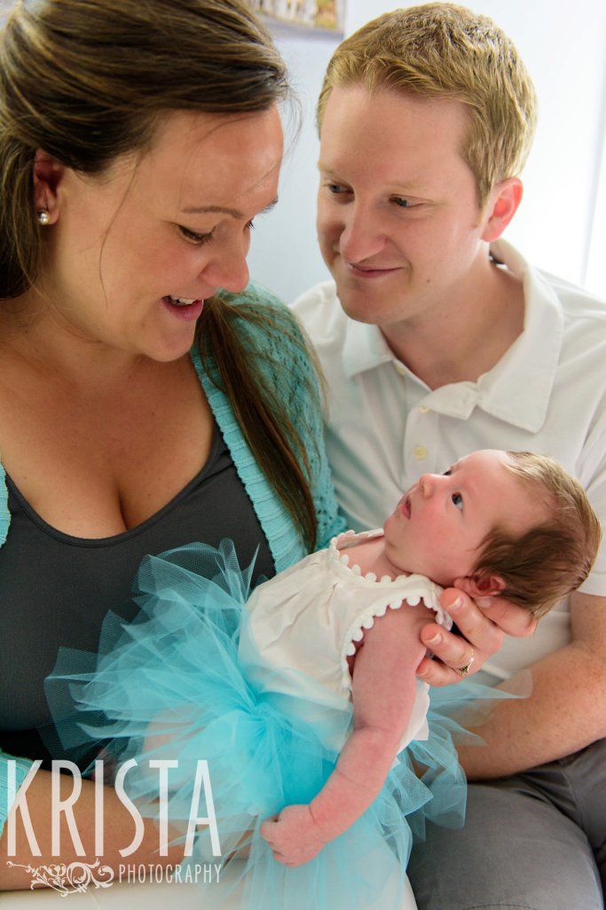 family with newborn baby girl in aqua tutu father gazing adoringly at mother who is gazing adoringly at baby