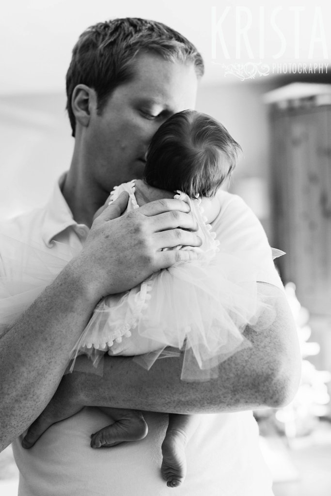black and white of father holding newborn baby girl in arms during lifestyle family portrait session