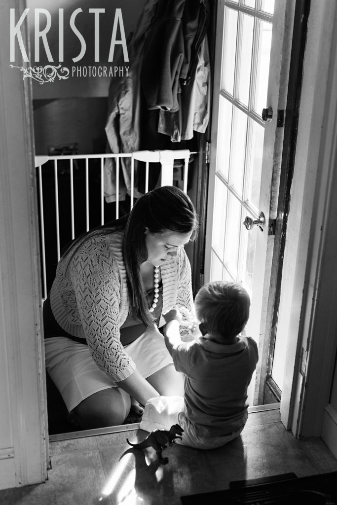 black and white image of mother helping toddler son put on shoes to go outside during lifestyle family portrait session