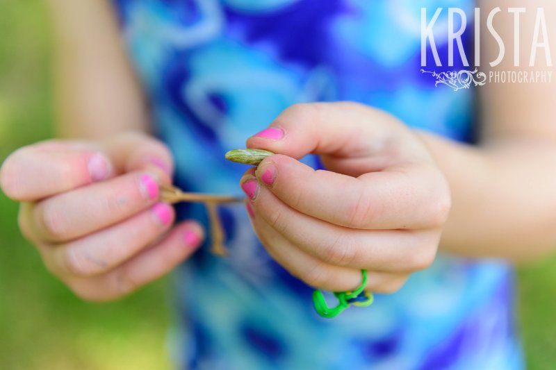 two sisters concentrating on making flower jewelry during springtime mini portrait sessions in New England
