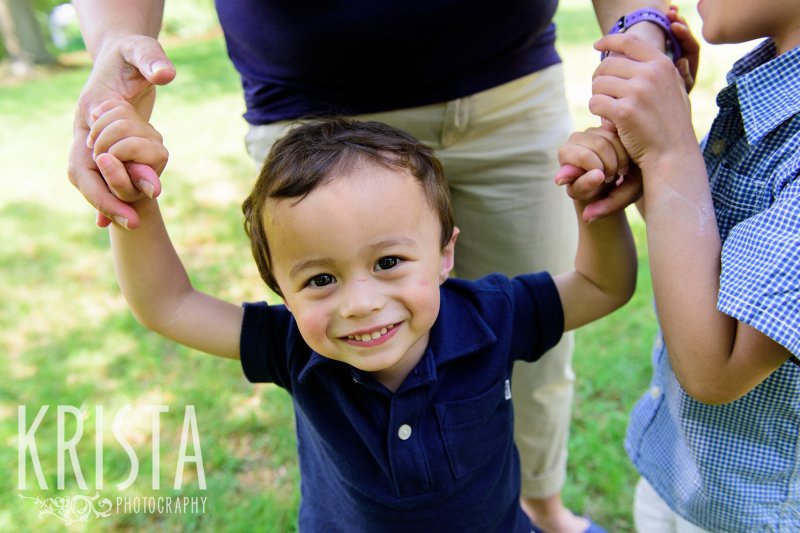 toddler boy in collared shirt holding mom's hands during springtime mini portrait session in New England