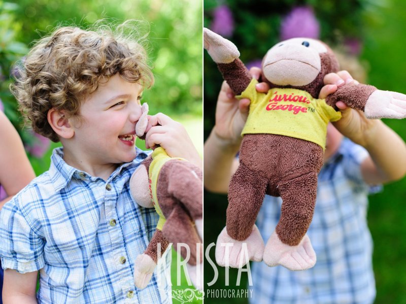 little boy with his curious george stuffed animal among green trees during springtime mini portrait sessions in New England