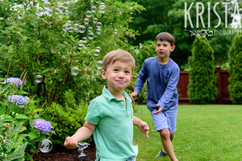 brothers playing with bubbles in backyard during lifestyle portrait session at home