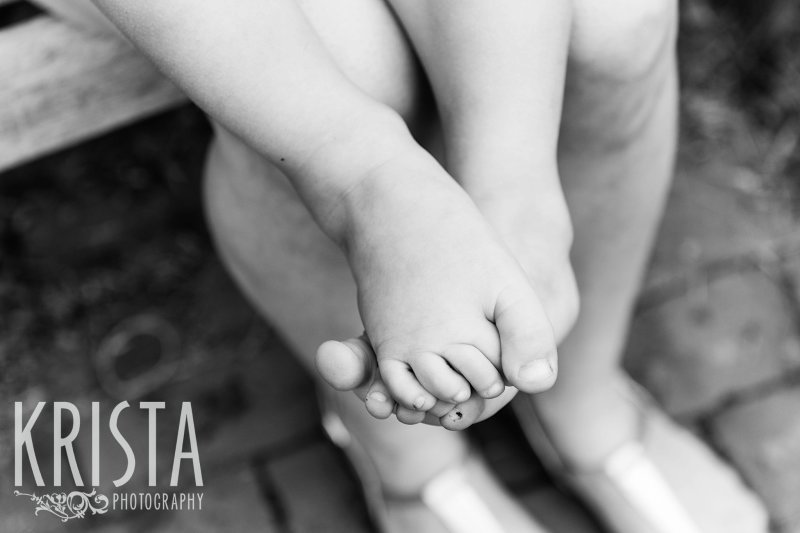 black and white of little boys feet while sitting on mother's lap
