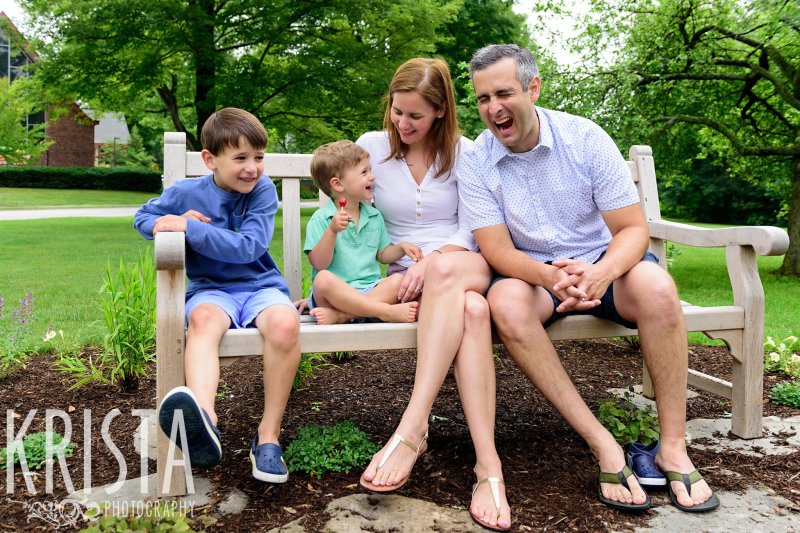 family seated on outdoor bench laughing 