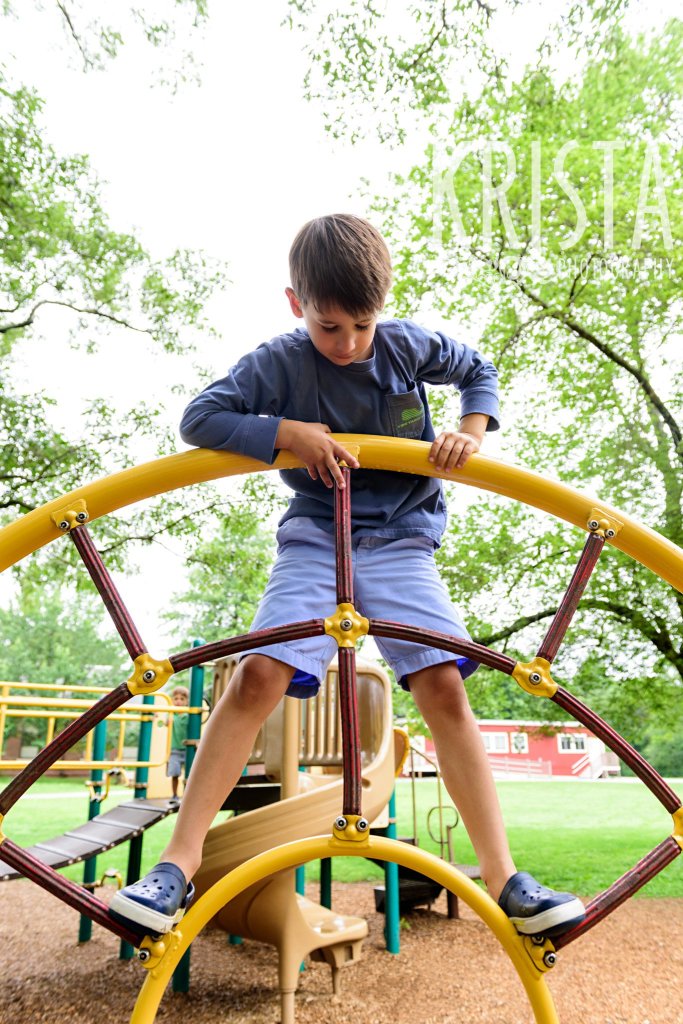 young boy in blue climbing structure on playground