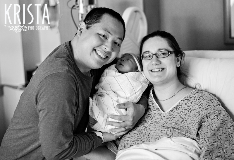 black and white image of brand new family after birth of baby boy in hospital