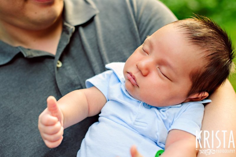 newborn baby boy giving thumbs up while sleeping during outdoor lifestyle portrait session at family's home