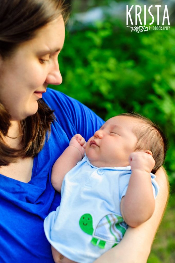 new mother gazing adoringly down at newborn baby son during outdoor lifestyle portrait session at family's home