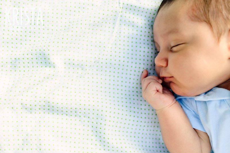 sleeping newborn baby boy on blanket during outdoor lifestyle family portrait session at home