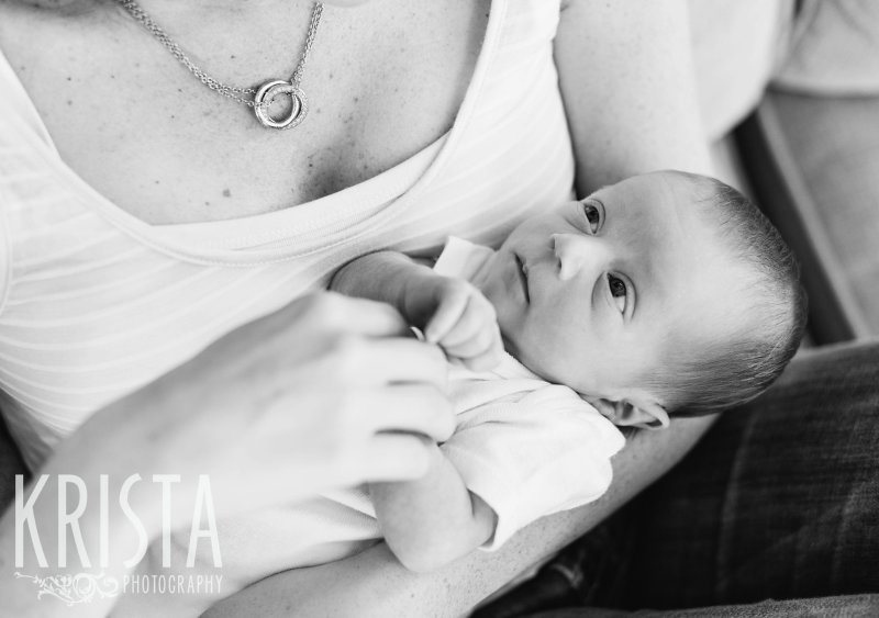 black and white image of mothers arms holding newborn baby boy during portrait session at home