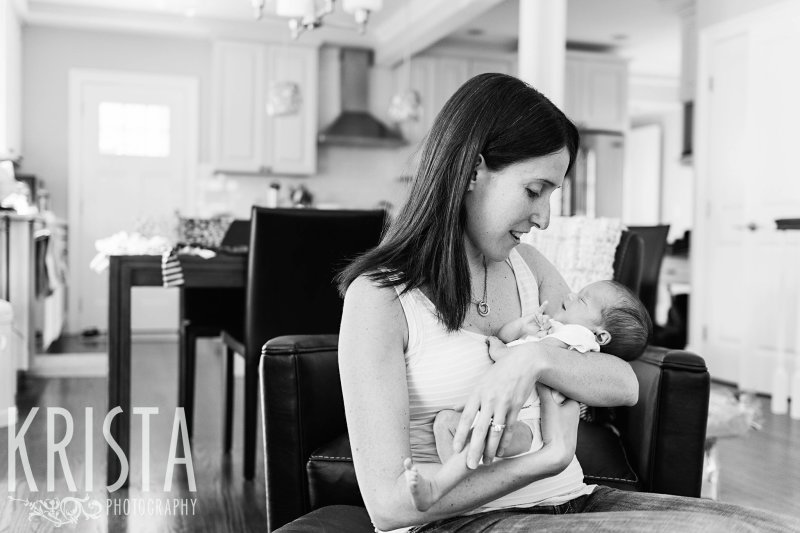 black and white of mother cuddling newborn baby twin in home during portrait session