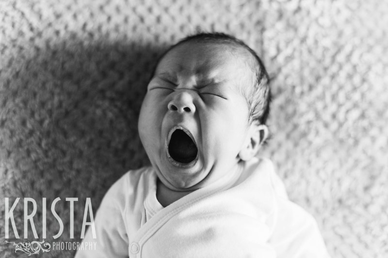 black and white image of newborn baby boy yawning big