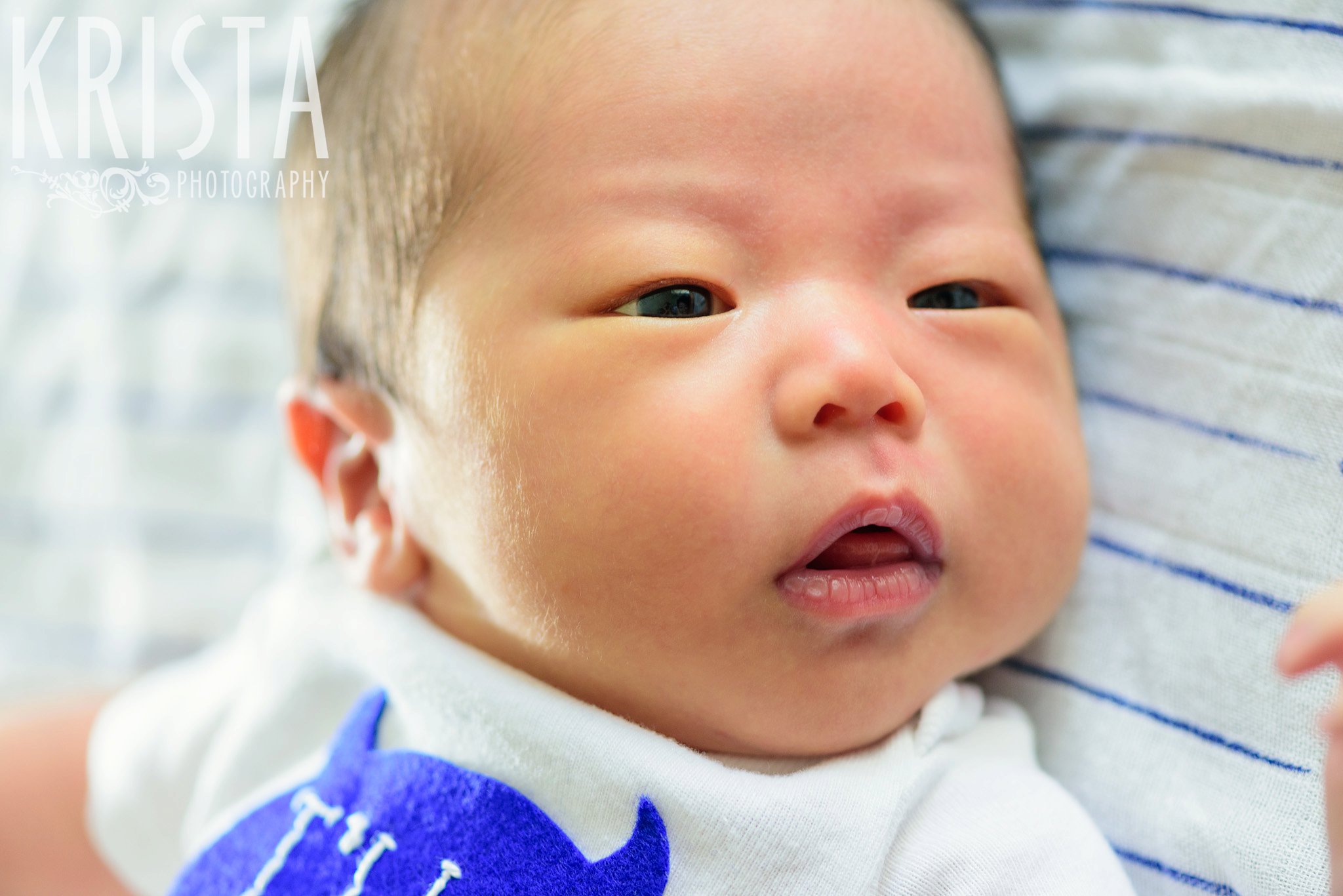 newborn baby boy laying on blue striped blanket