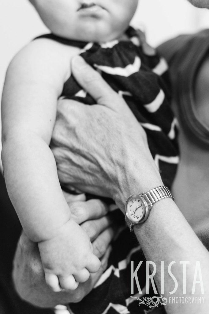 black and white image of baby girl in grandmother's arms trying to wake up from nap for lifestyle portrait session in home
