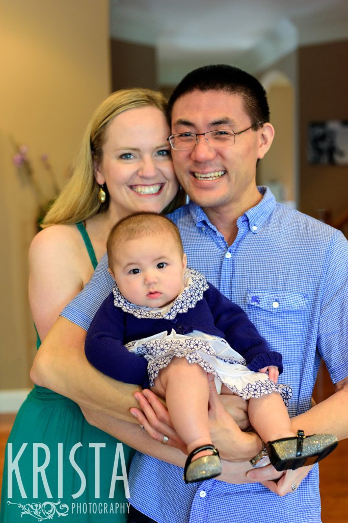 bi-racial family holding baby girl in blue lace dress during lifestyle portrait session at home