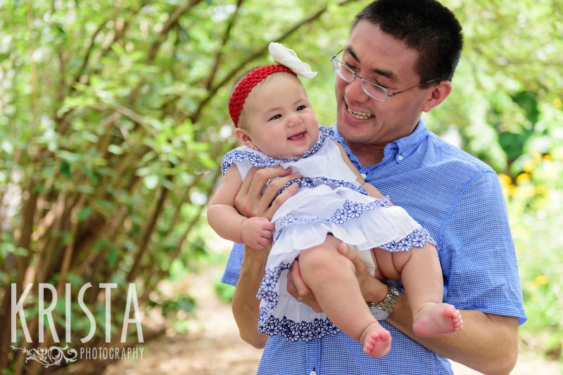baby girl in father's arms among trees in their yard during lifestyle portrait session