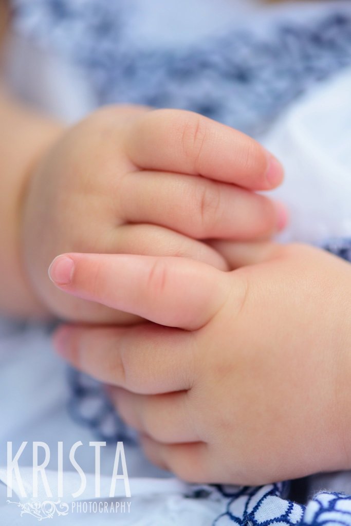 pudgy little baby girl fingers interlocked during lifestyle portrait session at home