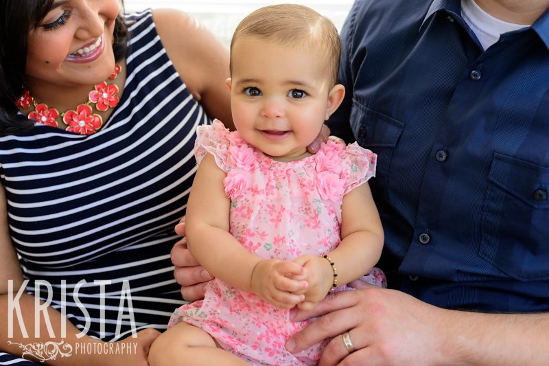 adorable baby girl in pink floral romper on mom's lap during lifestyle portrait session at home