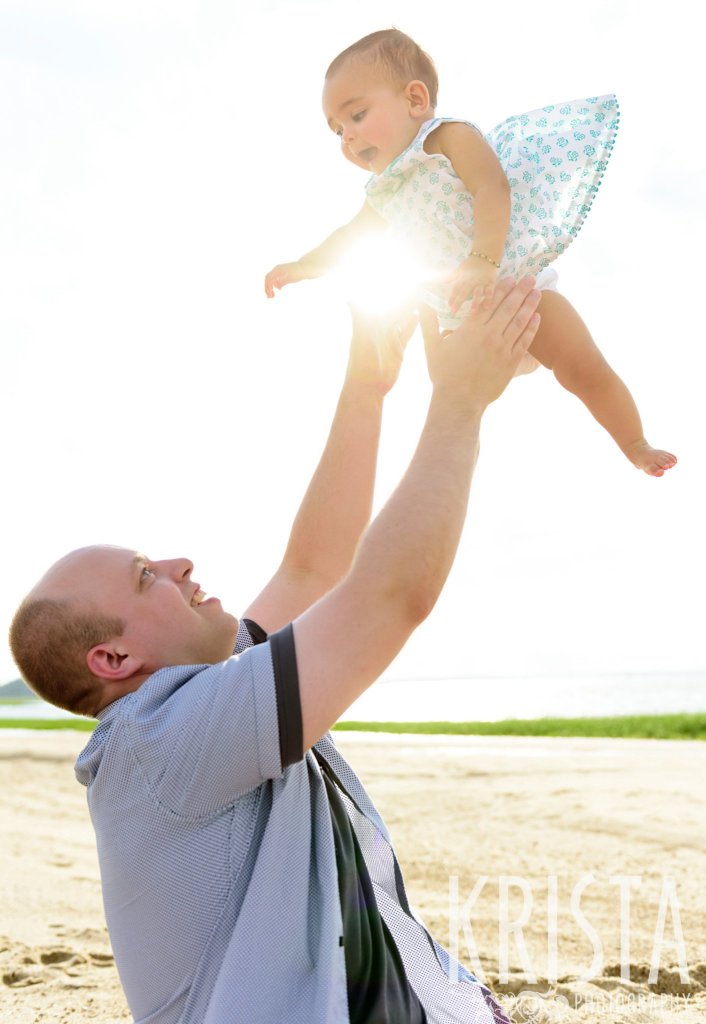dad tossing baby girl into sunset sky on beach of Cape Cod during lifestyle portrait session
