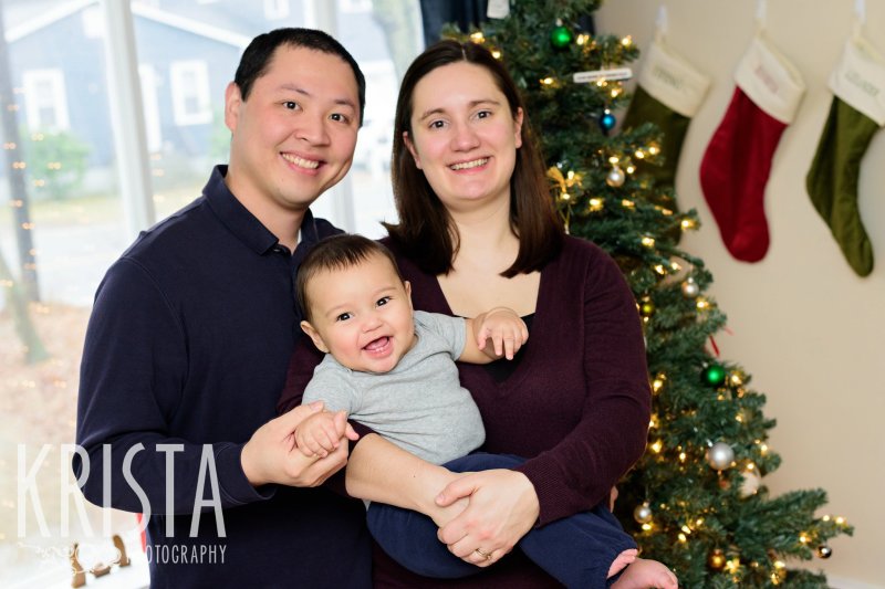 family with six month old baby boy in front of Christmas tree during lifestyle portrait session at family home