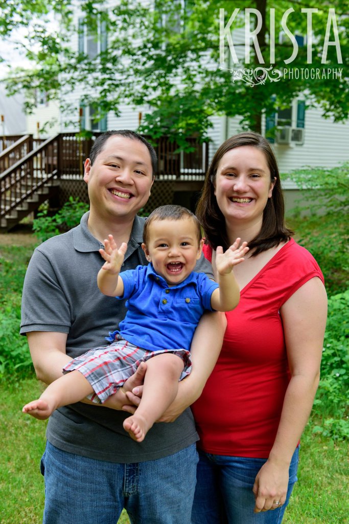 adorable family of three with one year old boy in blue collared shirt and plaid shorts during lifestyle portrait session with family
