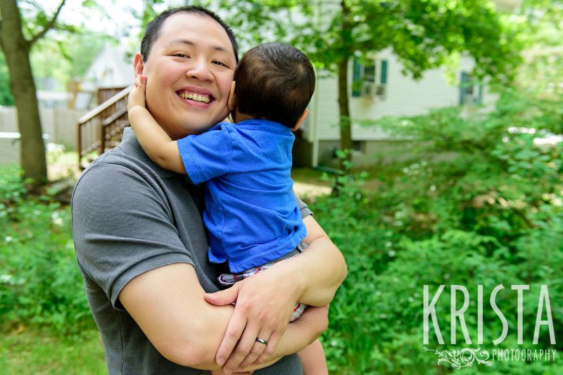 one year old boy in blue collared shirt hugging dad's neck tightly during lifestyle portrait session at home
