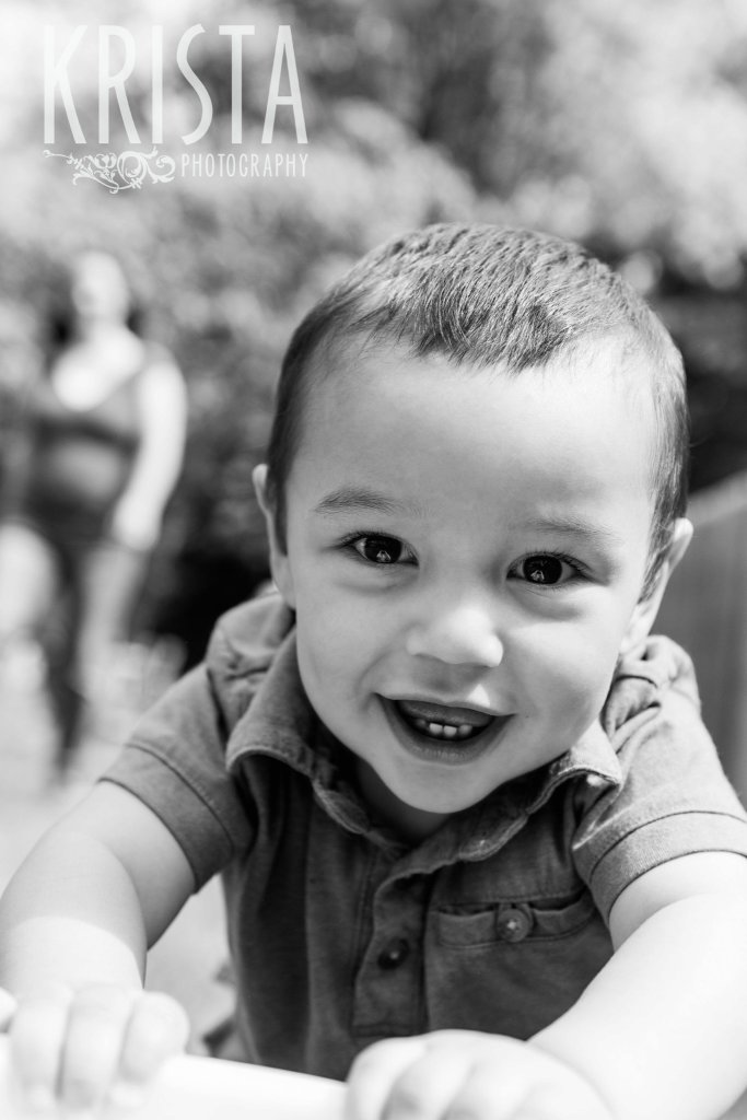 black and white image of one year old boy smiling a big toothy smile during lifestyle portrait session at home