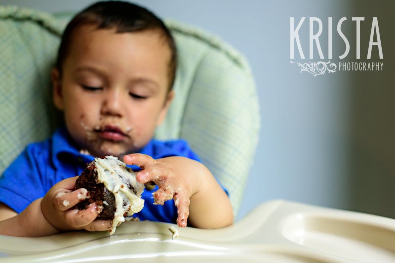 one year old birthday boy trying cake for first time during lifestyle portrait session at home