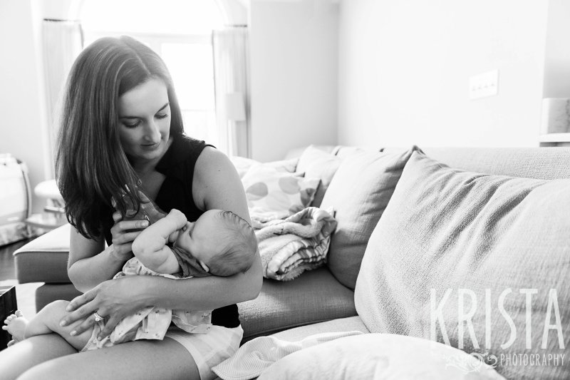black and white image of mother feeding three month old baby girl a bottle during lifestyle portrait session at family's home