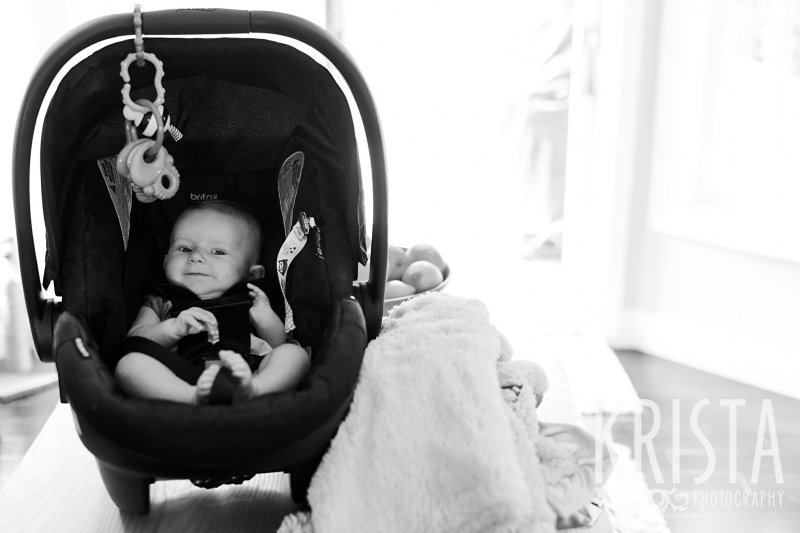 black and white image of three month old baby girl in carseat at home during lifestyle portrait session at home