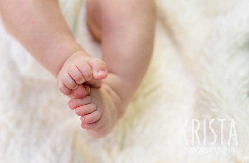 three month old baby girl little feet on cream furry blanket during lifestyle portrait session at home