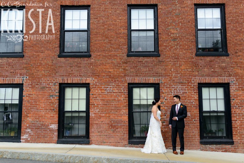 bride and groom in front of brick wall © Krista Photography