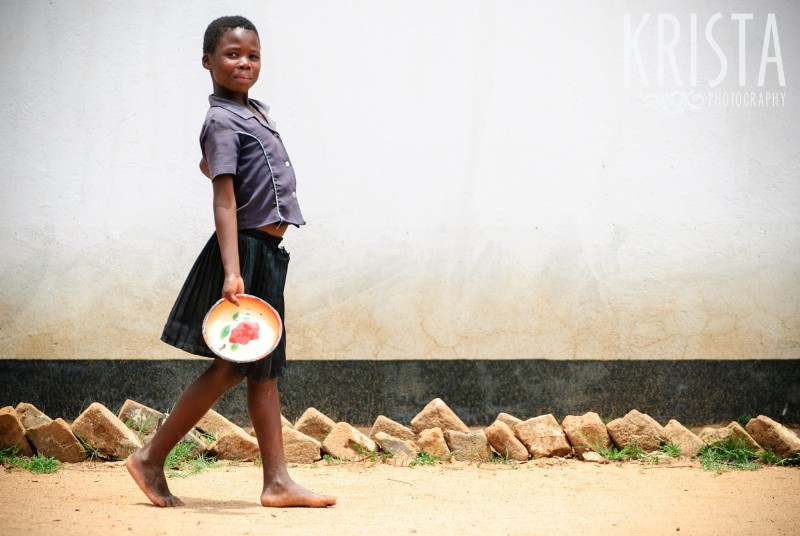 A girl in rural Zimbabwe carries a plate to get her free lunch at school. Krista Guenin | Humanitarian Photographer