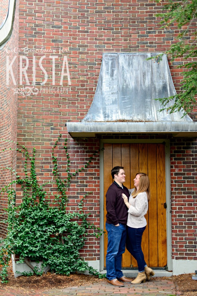 couple snuggling under a metal awning at St. Anselm College - Saint Anselm Engagement